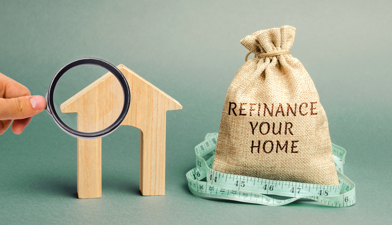Stacked bag titled "REFINANCE YOUR HOME" with tape measure around it along with a hand to the left of it holding a magnifying glass in front of a miniature house.